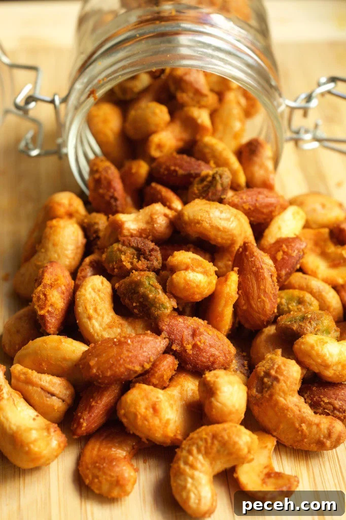 Crispy Buffalo-Spiced Nuts Recipe for Game Day Snacks 4 Buffalo spiced nuts spilling out of a glass jar on a cutting board