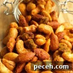 Crispy Buffalo-Spiced Nuts Recipe for Game Day Snacks 5 Buffalo spiced nuts spilling out of a glass jar on a cutting board