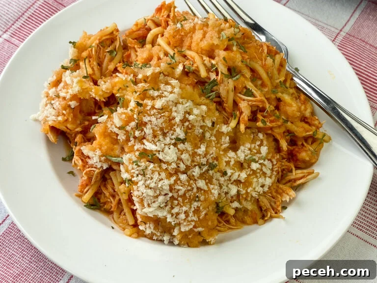 One-Pot Slow Cooker Chicken Parmesan Recipe 2 White plate with shredded chicken mixed in with spaghetti pasta and sauce with a light coating of Italian bread crumbs on top