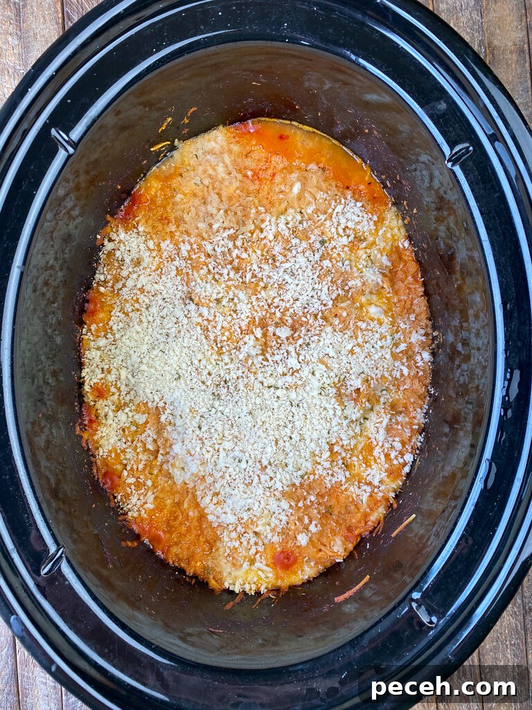 One-Pot Slow Cooker Chicken Parmesan Recipe 10 Cooked parmesan chicken with pasta in a crock pot on a wooden counter top