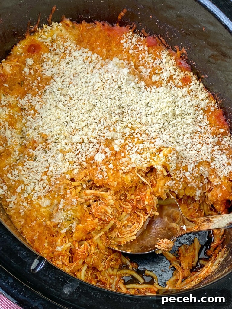 One-Pot Slow Cooker Chicken Parmesan Recipe 11 Close up bread crumbs on cheesy chicken parmesan with spaghetti all made in a large crock pot