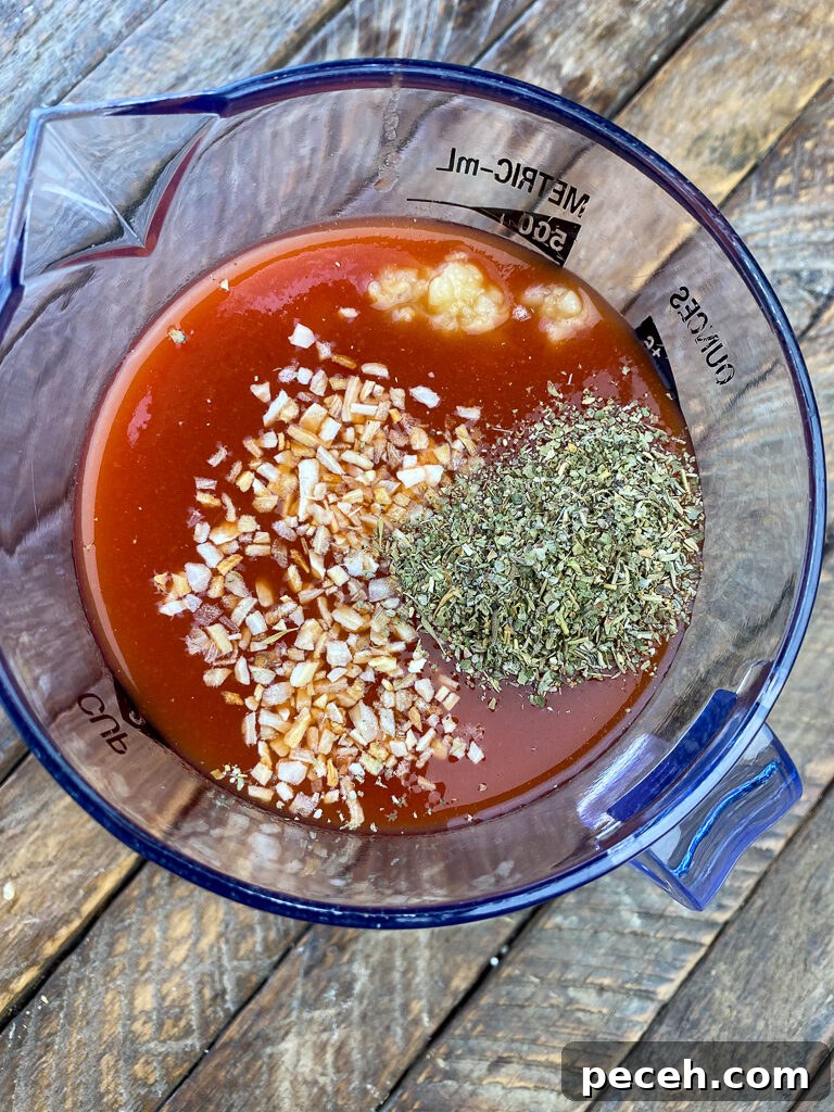 One-Pot Slow Cooker Chicken Parmesan Recipe 5 Granulated onion, minced garlic and Italian seasoning poured on tomato juice in a measuring cup on a wooden countertop