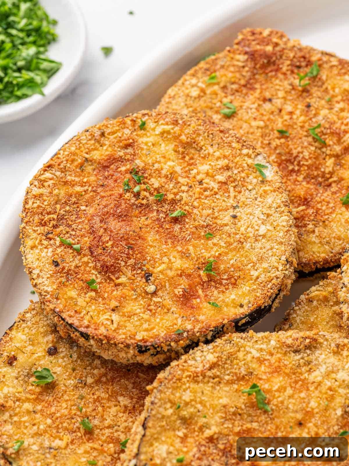 Crispy Air-Fried Eggplant Slices: Quick Restaurant-Style Recipe 8 Golden, crispy fried eggplant garnished with parsley.