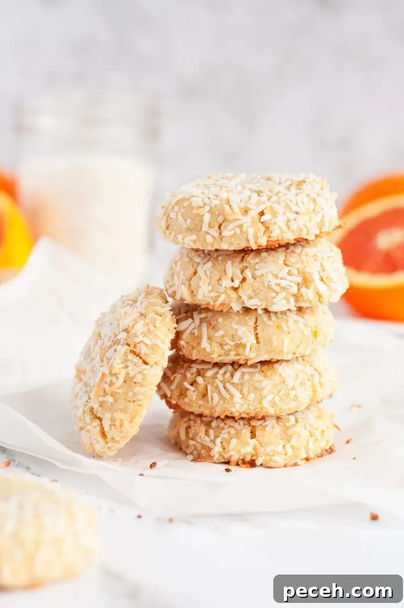 A tall stack of coconut orange cookies that are covered in white shredded coconut.