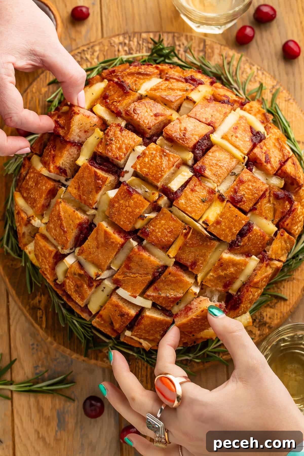 Cranberry and Brie Pull-Apart Bread 5 Two sets of hands reaching in to take pieces of cranberry pull apart bread.