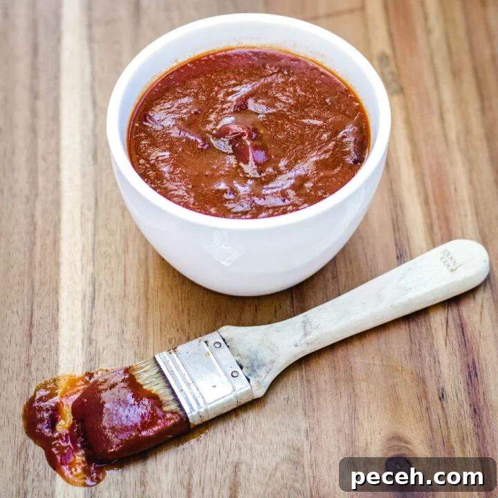Small bowl of sweet and spicy BBQ sauce with a brush full of sauce in front of it.