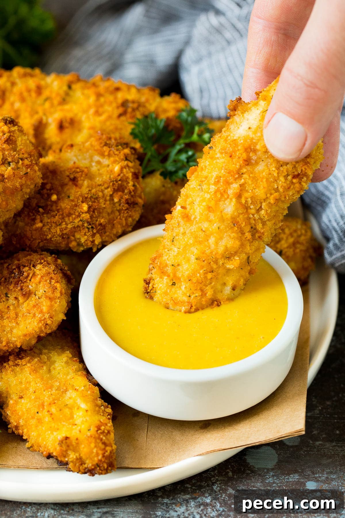 Homemade Honey Mustard Sauce Recipe for Dipping and Dressing 5 A chicken finger being dipped into honey mustard sauce.