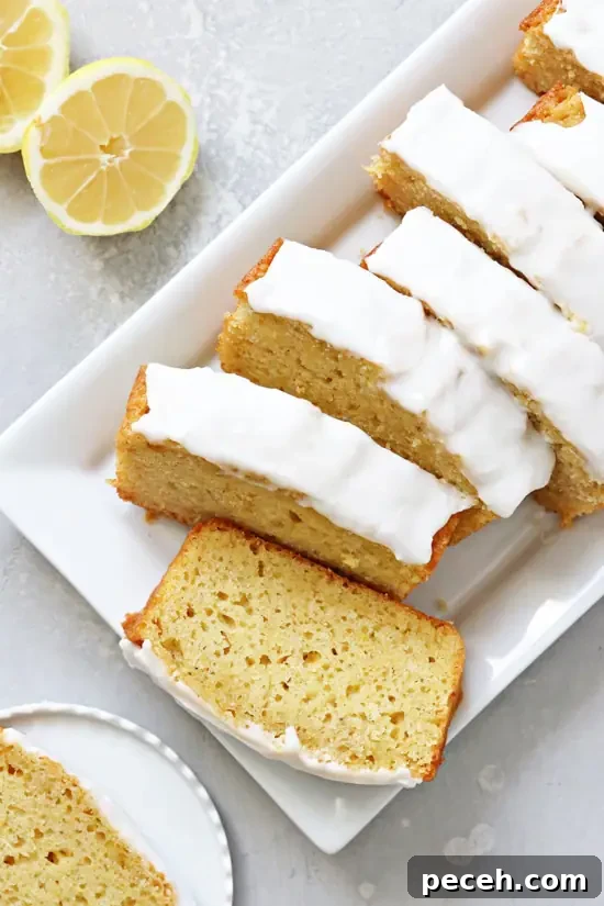 Dairy-Free Lemon Drizzle Cake Recipe — Zesty Moist Loaf 5 Sliced Dairy Free Lemon Loaf on a white platter.