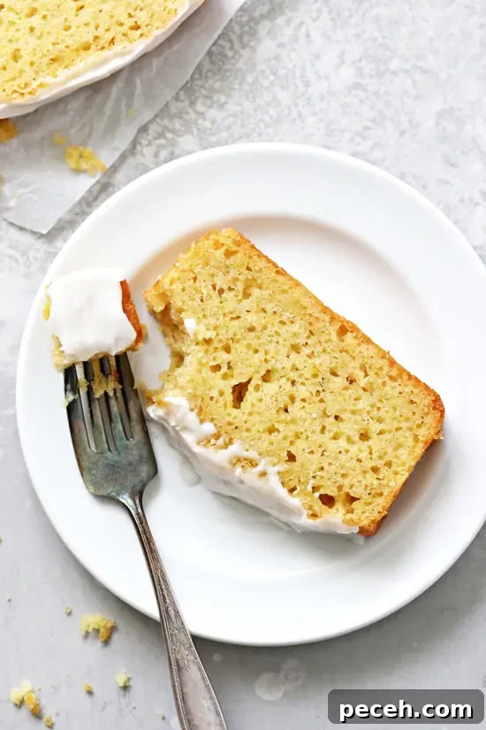 Dairy-Free Lemon Drizzle Cake Recipe — Zesty Moist Loaf 6 A slice of Dairy Free Lemon Drizzle Loaf with a bite taken out with a fork.