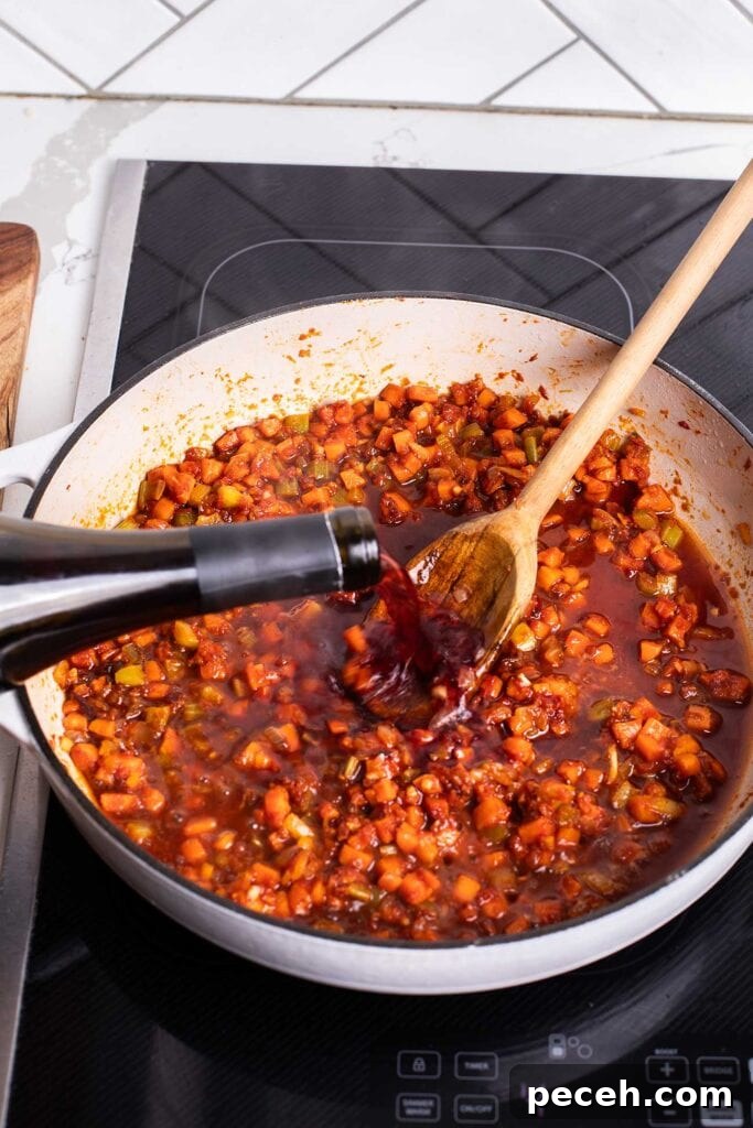 Braised Beef Short Rib Ragu Recipe — Slow-Cooked Italian Comfort 7 Wine being poured in to the pan, deglazing the browned bits left behind by the vegetables.
