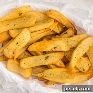Air fryer steak fries in a basket, garnished with parsley flakes.