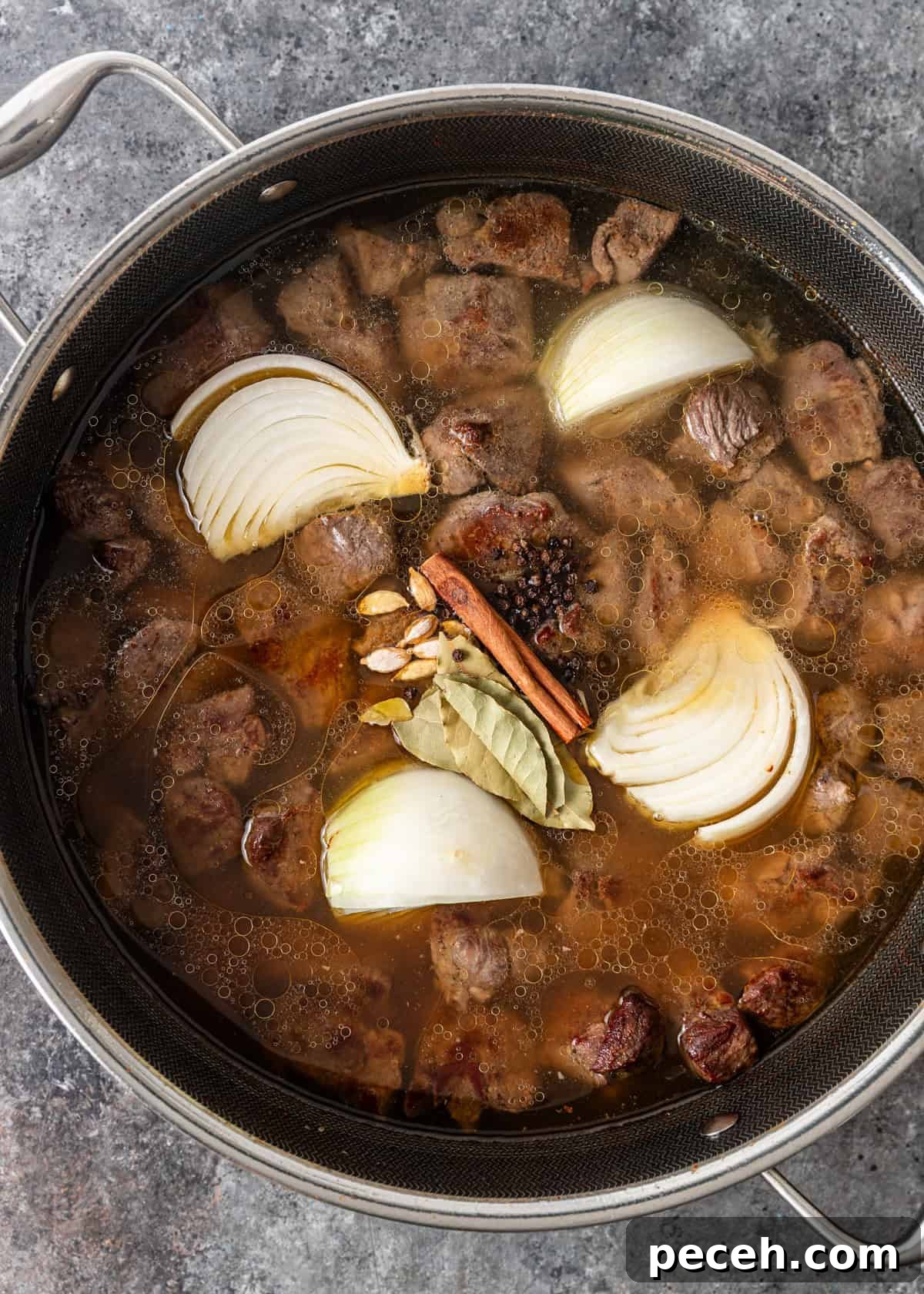 Authentic Jordanian Mansaf Recipe: Traditional Bedouin Feast 6 overhead process shot: water, cardamom, bay leaves, cinnamon, peppercorns, and onion added to cooked lamb