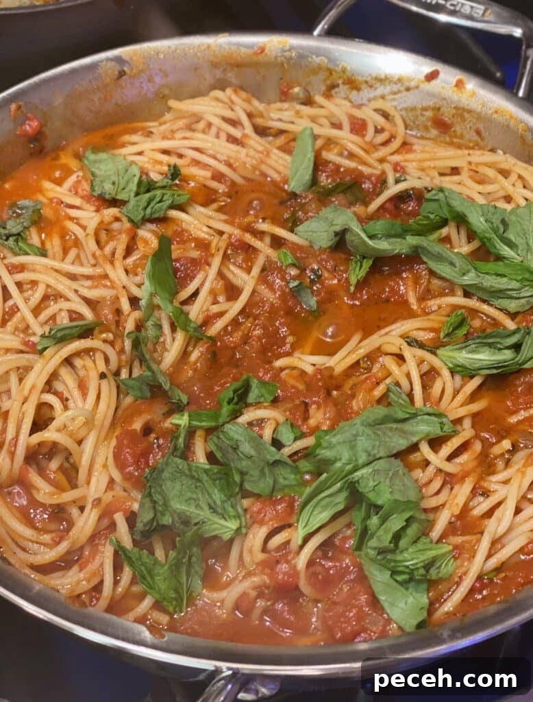 Authentic Meatless Sugo: Italian Tomato and Basil Sauce Recipe 9 Large skillet of spaghetti tossed with tomato basil sugo recipe and fresh basil leaves.