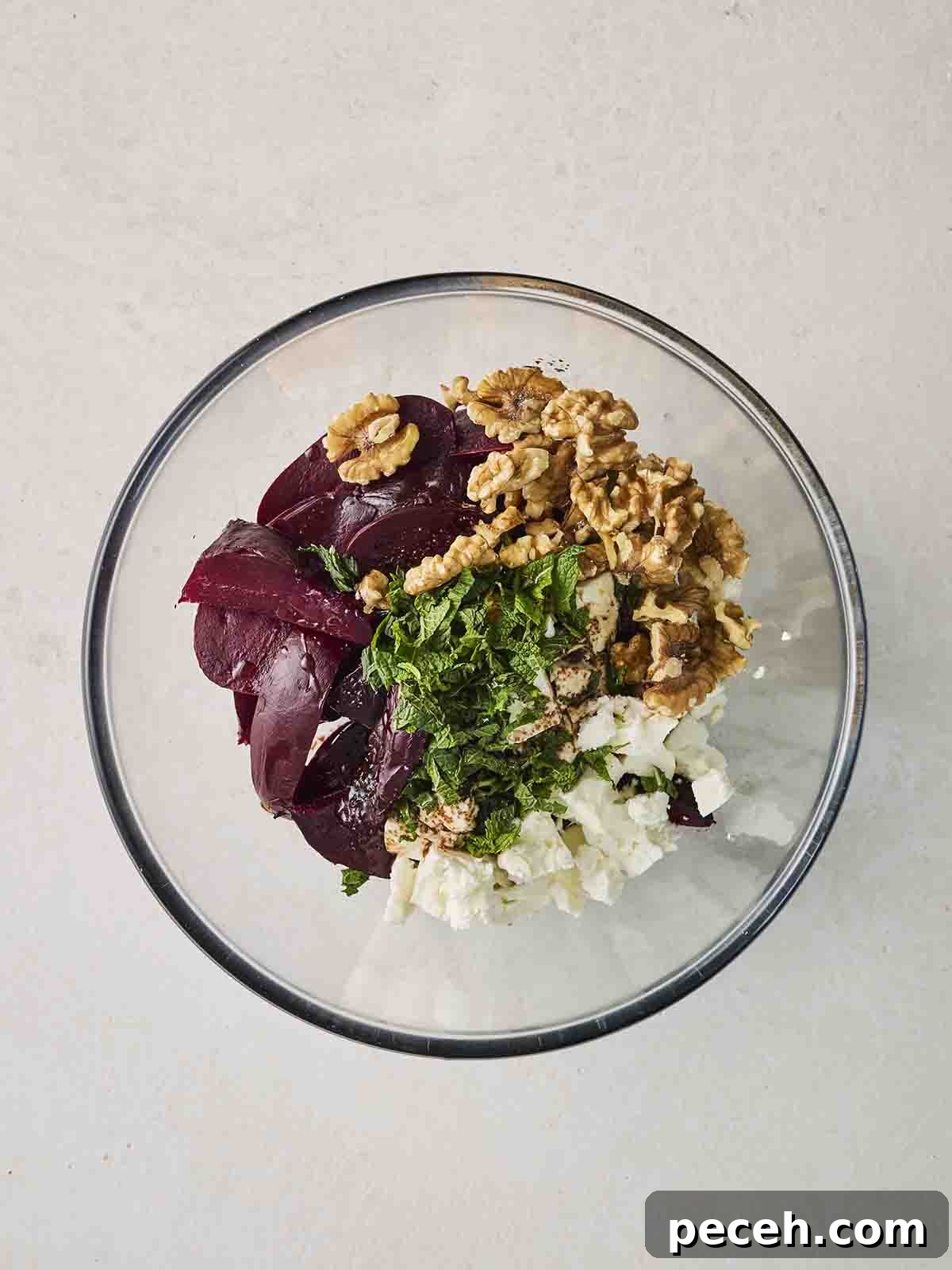 Lots of ingredients that make up a Beetroot Salad in a glass bowl, ready for mixing.
