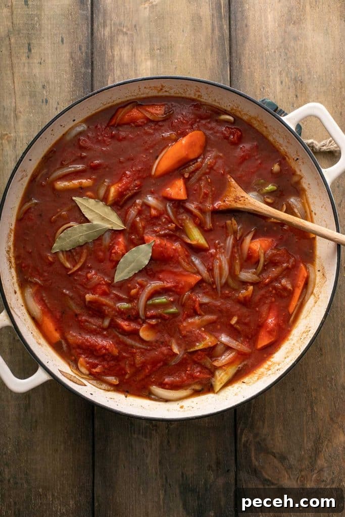 crushed tomatoes, broth, bay leaves and veggies simmering in a dutch oven