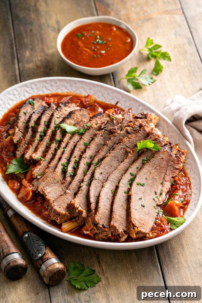 Think slices of brisket served over veggies on a white plate