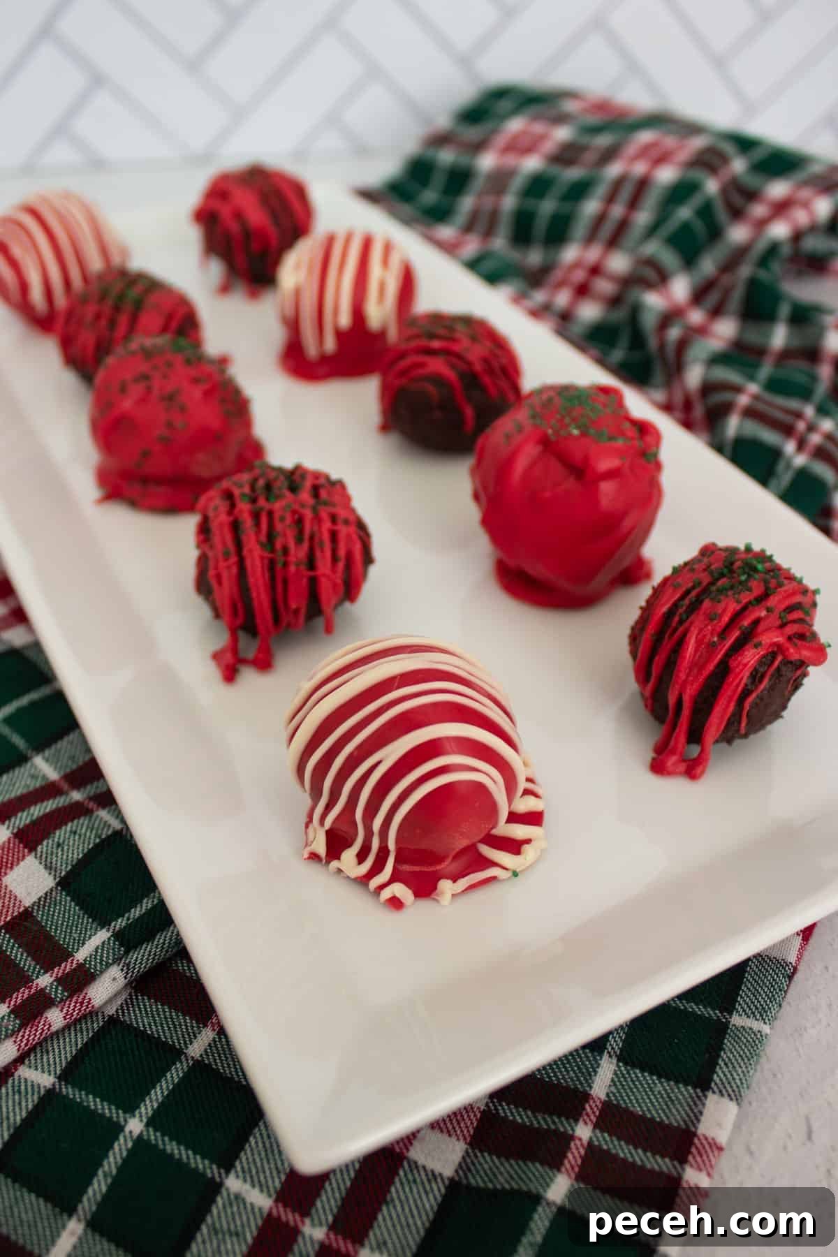 Decadent Christmas Truffles: Festive Homemade Chocolate Treats 2 Red, white, and green decorated chocolate truffles on a white serving platter.