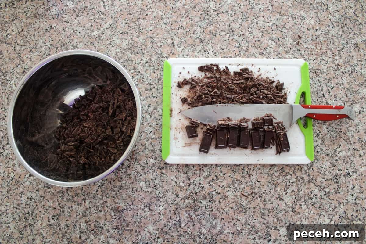 Decadent Christmas Truffles: Festive Homemade Chocolate Treats 4 Chocolate bars being chopped on a cutting board with some already chopped in a stainless steel bowl.