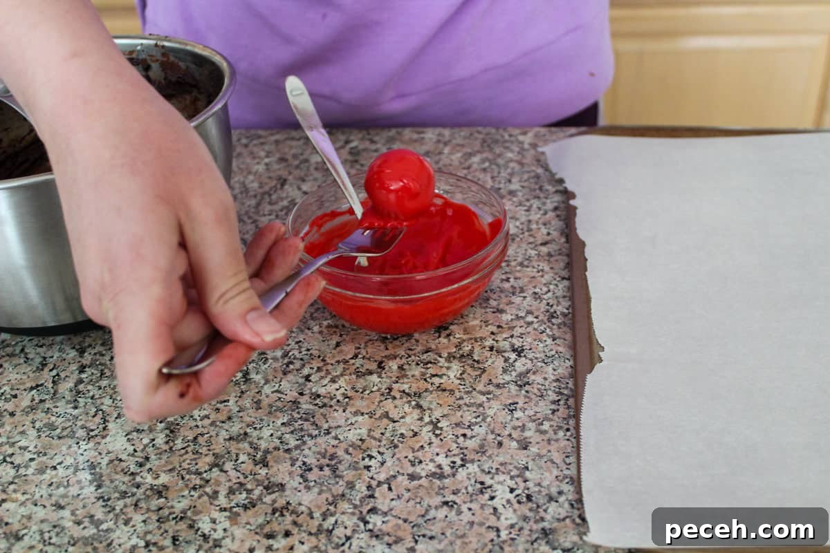 Decadent Christmas Truffles: Festive Homemade Chocolate Treats 8 A truffle being lifted out of melted red wafer coating with a fork.