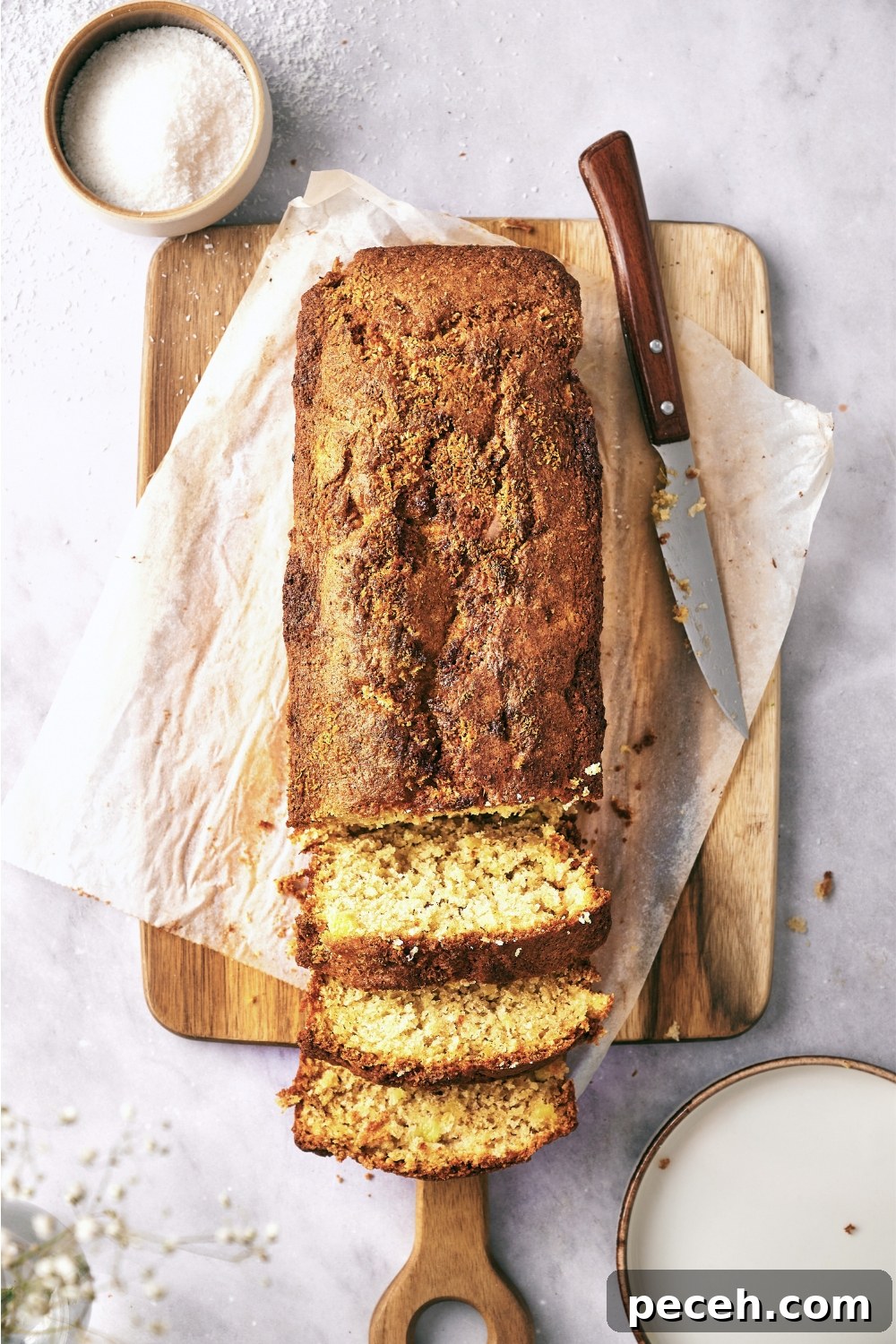 Tropical Hawaiian Banana Bread with Coconut and Macadamia Nuts 11 A wooden serving tray with a loaf of banana bread being sliced.