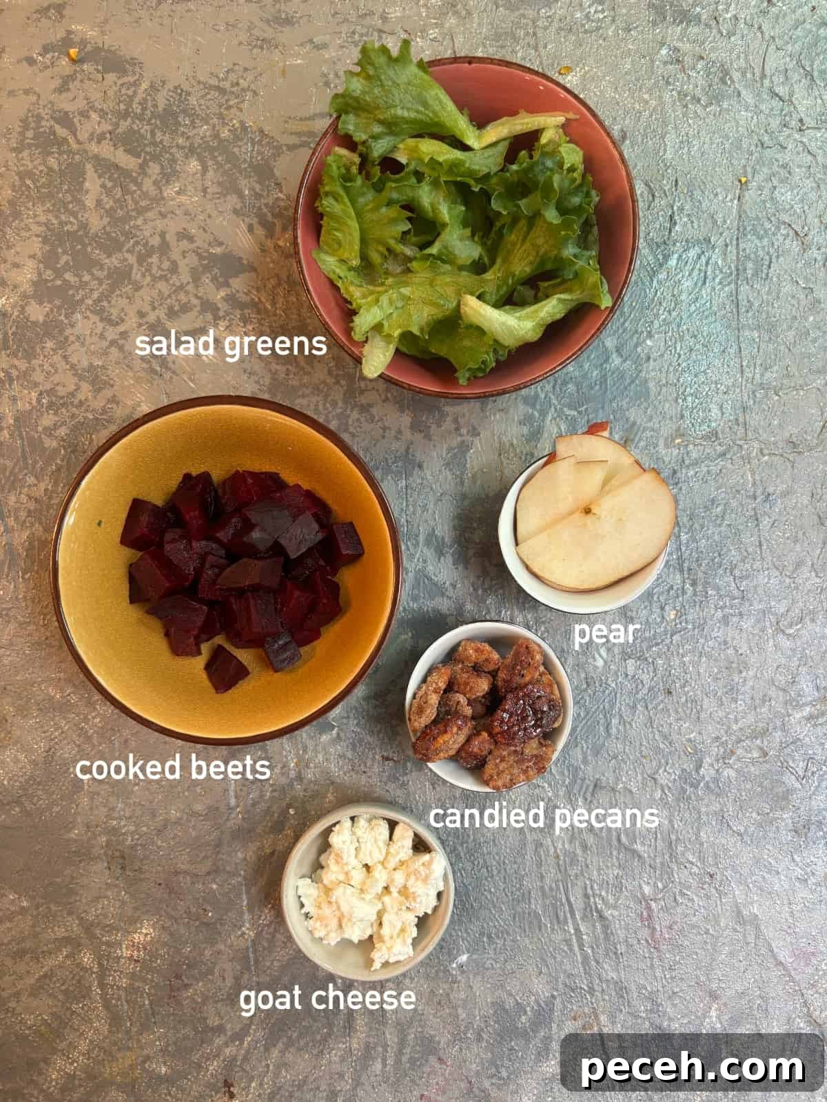 Roasted Beet Salad with Goat Cheese, Arugula and Walnuts 3 overhead image of the ingredients needed for beet salad. Each ingredient is in it's own small bowl and labeled with white text