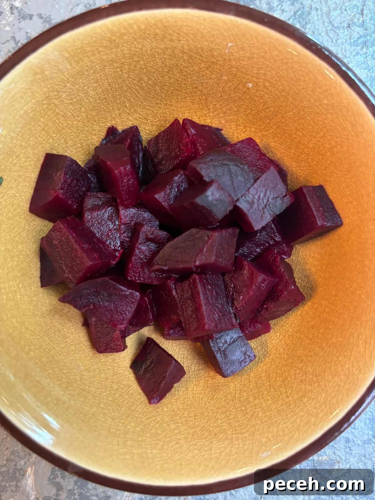 Roasted Beet Salad with Goat Cheese, Arugula and Walnuts 4 overhead image of a small yellow bowl with diced cooked beets