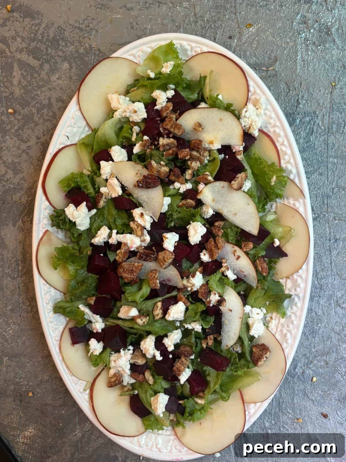 Roasted Beet Salad with Goat Cheese, Arugula and Walnuts 6 overhead image of a beet salad with goat cheese and pears on a white oval platter
