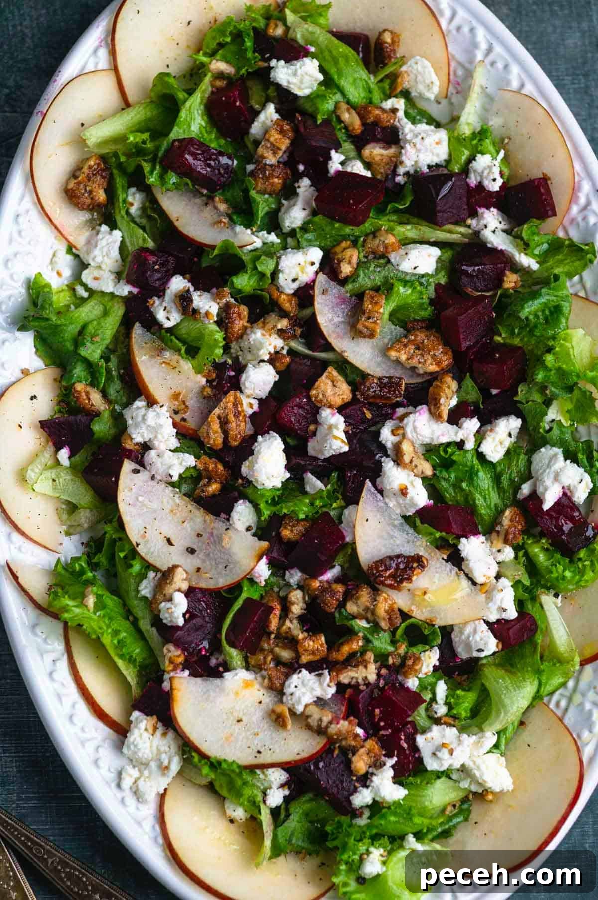 Roasted Beet Salad with Goat Cheese, Arugula and Walnuts 9 close up overhead image of a beet salad with goat cheese and pears on a white oval platter