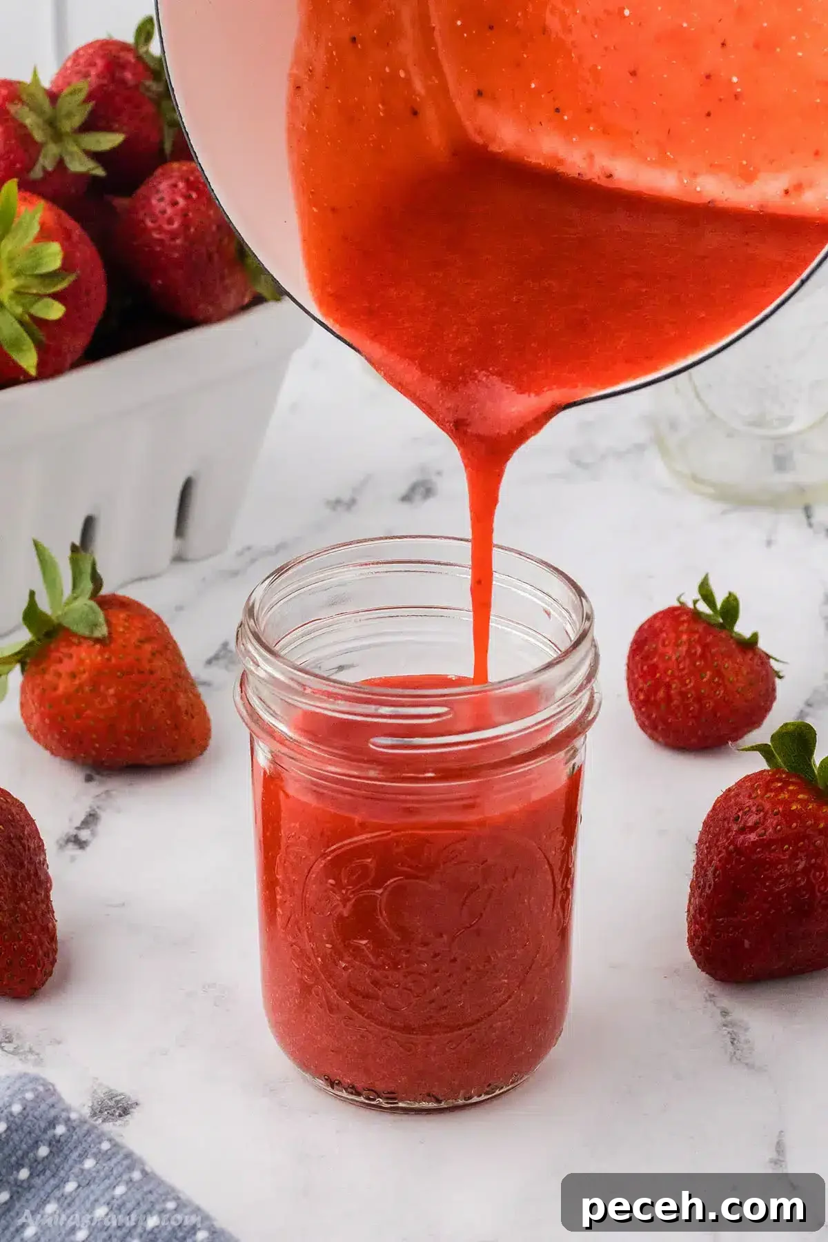Silky Strawberry Coulis Recipe for Desserts and Drinks 5 Strawberry sauce being poured into a jar.