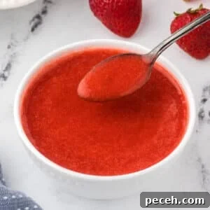 Strawberry coulis in a white bowl with a spoon.