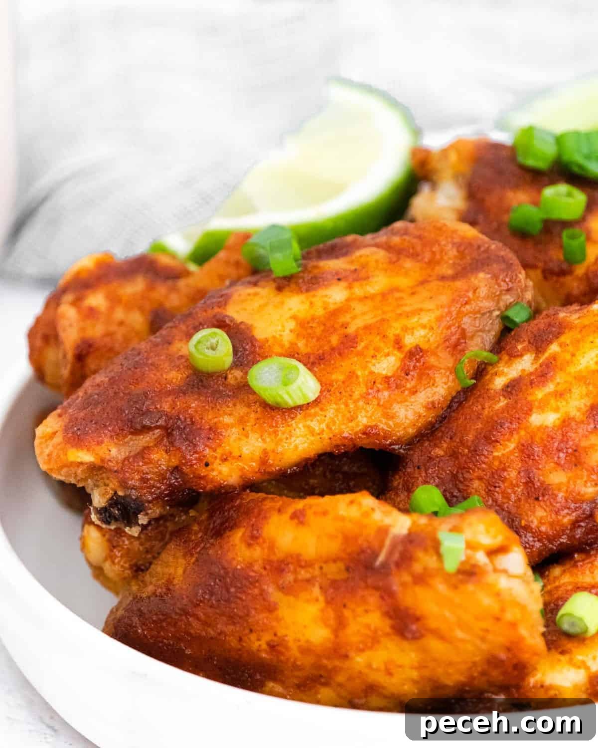 Chili Lime Chicken Wings with Tangy Dipping Sauce 11 Close up of chili lime wings on a white plate garnished with green onion.