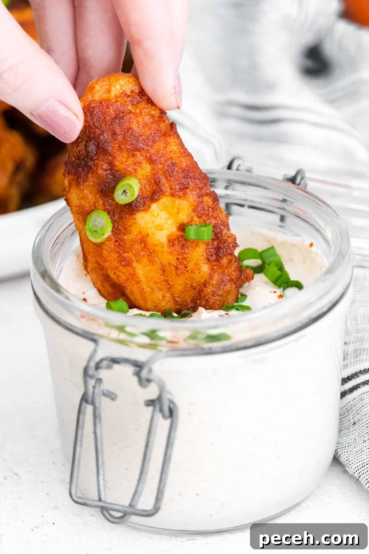 Chili Lime Chicken Wings with Tangy Dipping Sauce 6 Glazed wing being dipped into sauce.