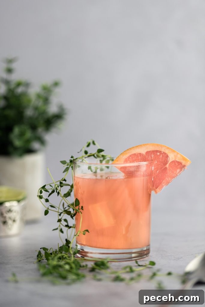 Sparkling Grapefruit Crush: Refreshing Citrus Cocktail Recipe 5 An individual cocktail with a grapefruit slice on the rim and fresh thyme along the side of the glass.