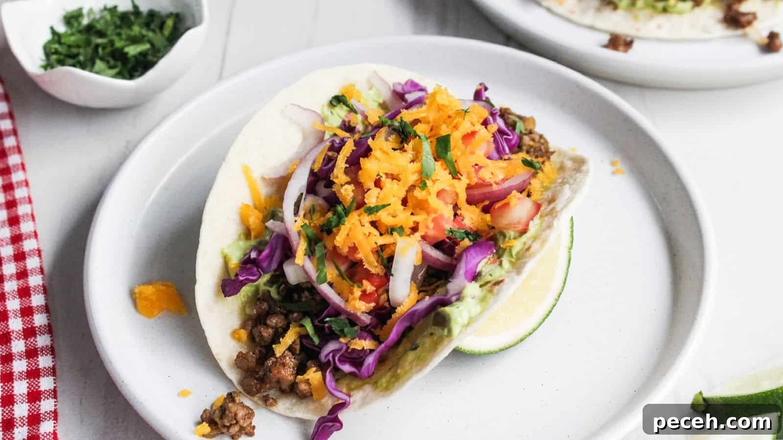 An easy dish to look forward to cooking every night: a colorful taco with ground meat, shredded carrots, red cabbage, and a slice of lime on the side.