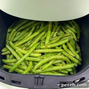 Green beans in an air fryer before cooking.