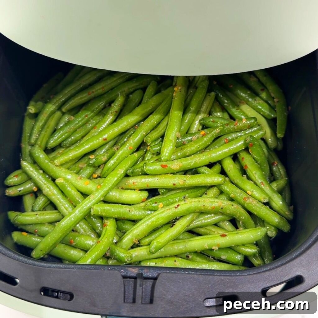 Green beans in an air fryer before cooking.