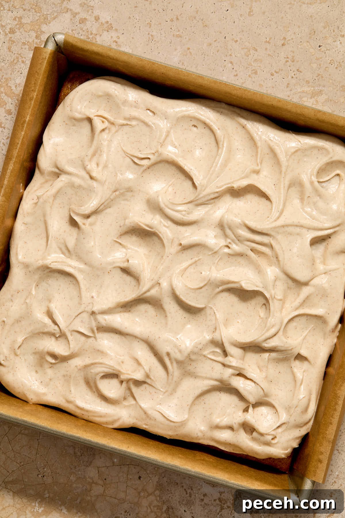 Vegan Chai-Spiced Layer Cake Recipe 12 Frosting spread out on top of the cake in the pan.