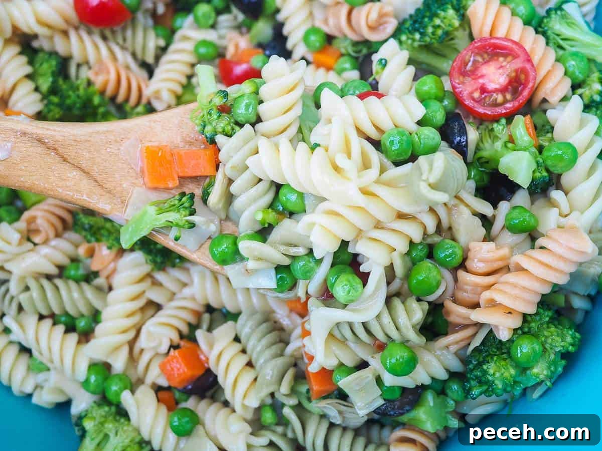 A scoop of pasta salad on a wooden spoon.