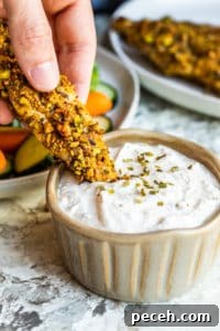 Chicken tender dipped in ranch Chicken tender being dipped into ranch dip in a gray bowl.