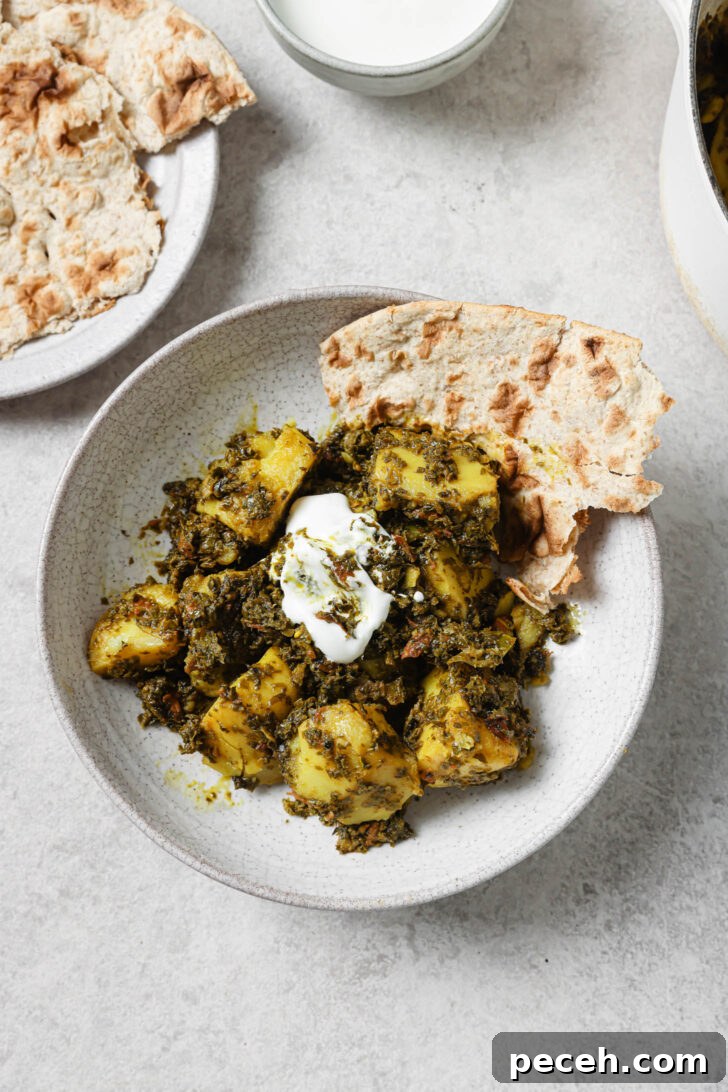 Authentic Aloo Methi (Potato & Fenugreek Leaves) Recipe from Mom-in-Law 2 Aloo Methi in a plate with a dollop of yogurt and naan on the side.