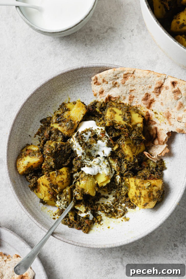 Authentic Aloo Methi (Potato & Fenugreek Leaves) Recipe from Mom-in-Law 3 Partially eaten Aloo Methi in a plate with a dollop of yogurt and naan on the side.