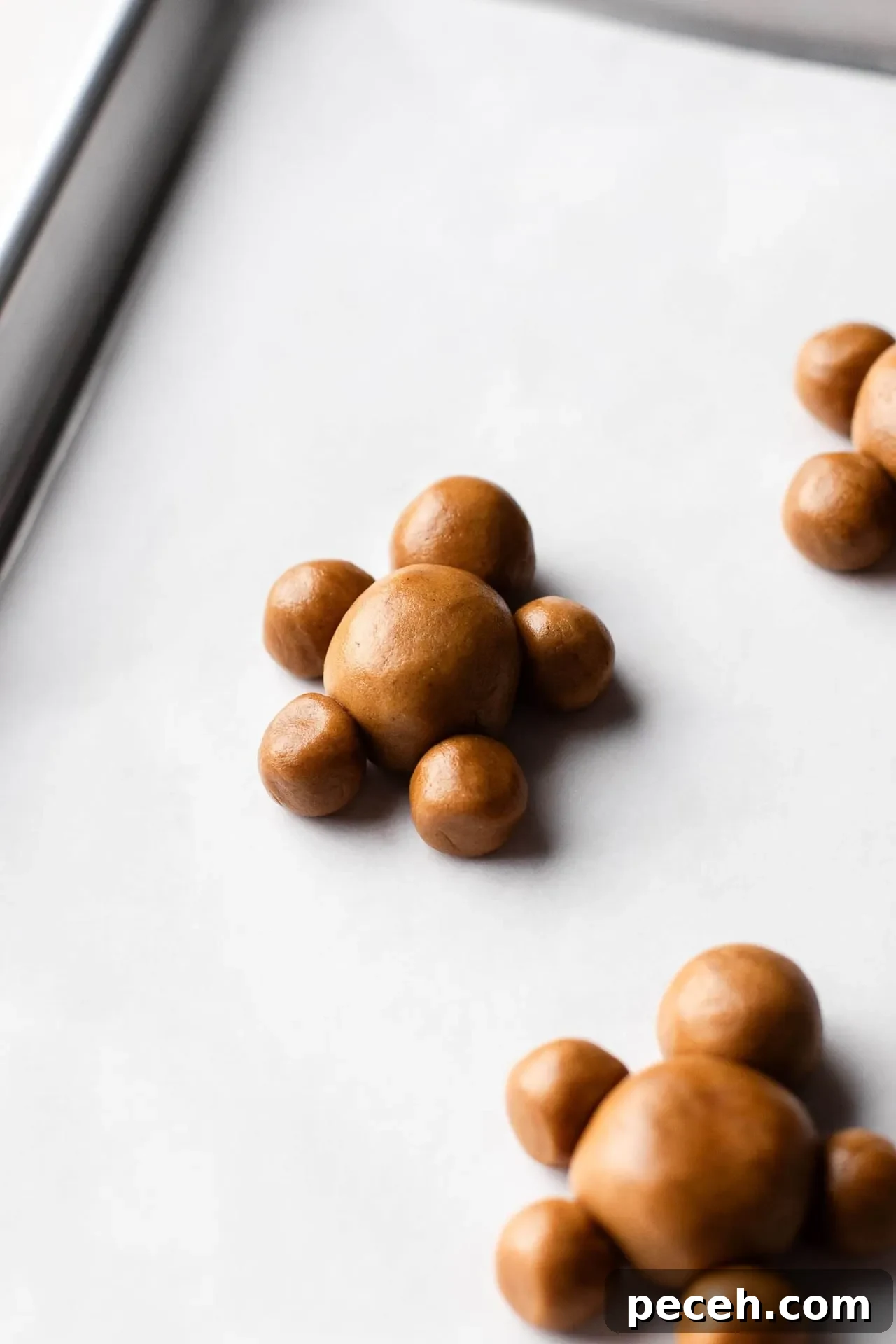 gingerbread dough balls arranged on parchment lined baking sheet in the shape of gingerbread men
