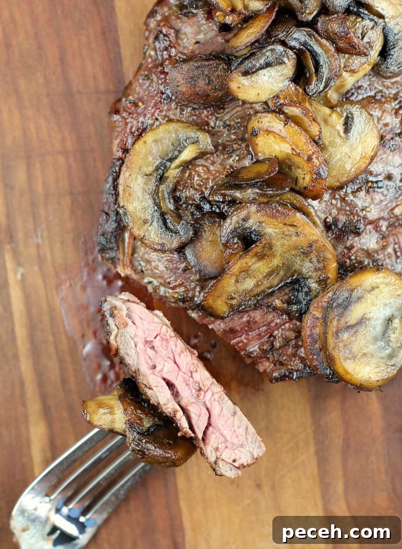 Garlic Butter Skirt Steak with Mushrooms — Bistro-Style Recipe 3 top view of finished steak cut with fork holding a piece to show doneness
