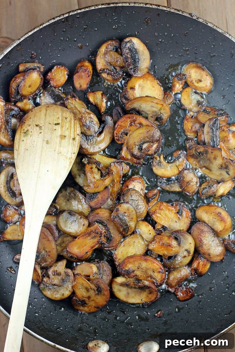 Garlic Butter Skirt Steak with Mushrooms — Bistro-Style Recipe 5 mushrooms in a skillet with wood spoon
