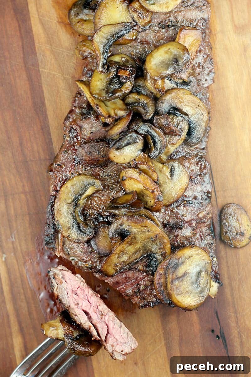 Garlic Butter Skirt Steak with Mushrooms — Bistro-Style Recipe 7 top down view of cooked steak on wood board with fork holding cut piece