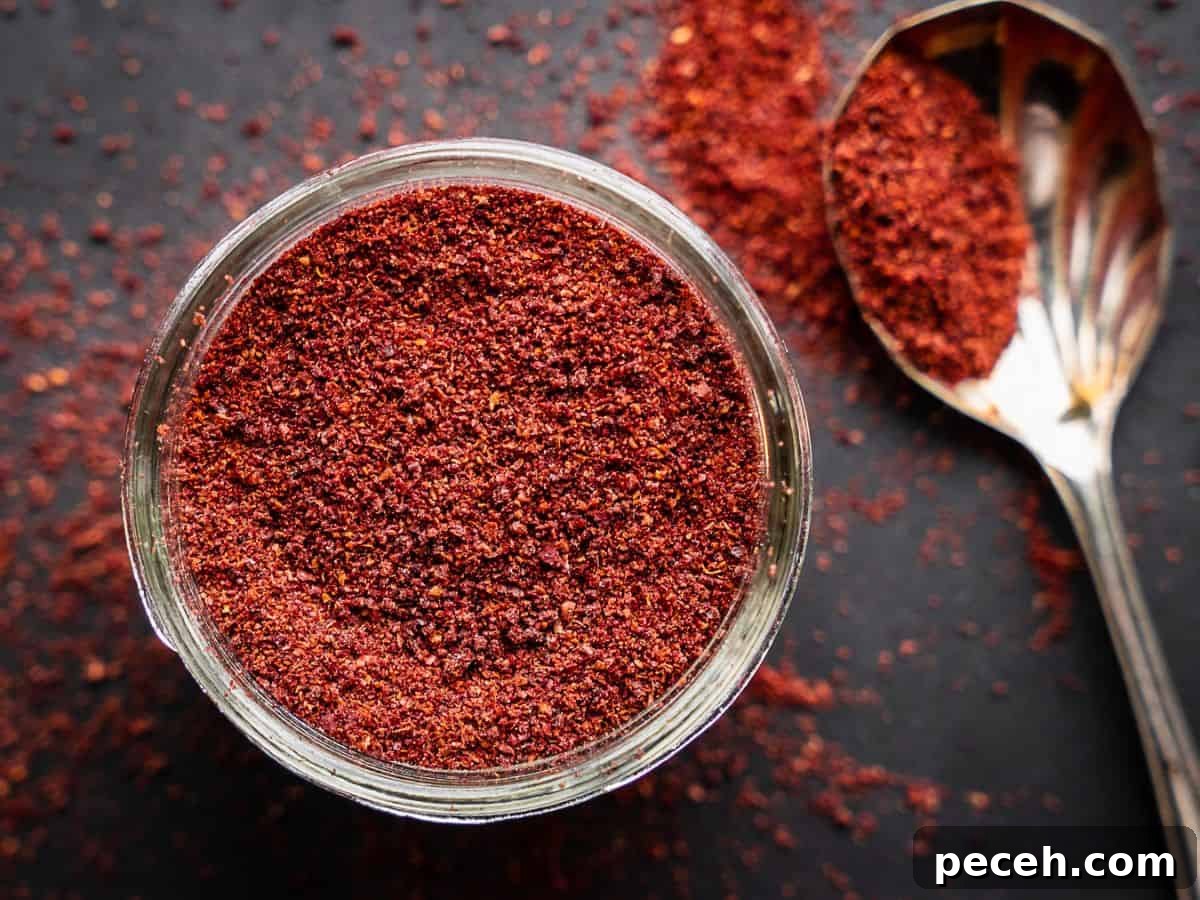 Sumac: History, Culinary Uses and Top Recipes 2 Sumac spice with spoon in an open mason jar.
