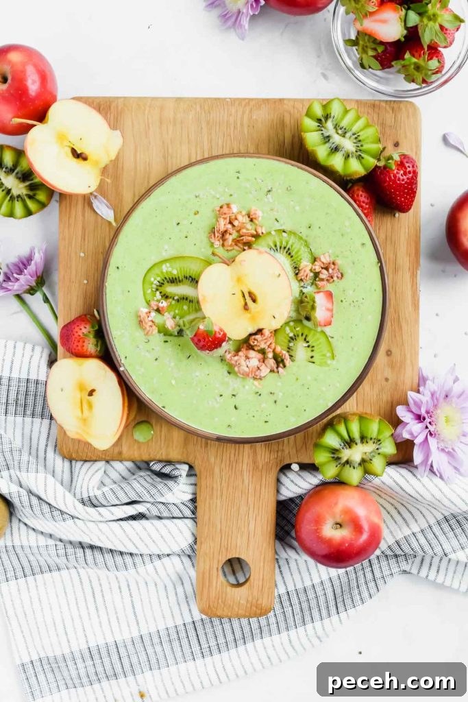 Mango Spinach Smoothie Recipe for Energy and Glow 11 Apple Kiwi Smoothie in bowl topped with kiwi, apple, strawberry slices, and granola.