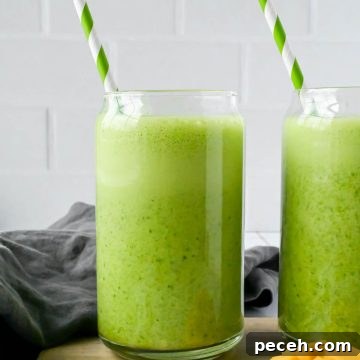 Mango Spinach Smoothie Recipe for Energy and Glow 12 two mango spinach smoothies with a green and white striped straw on white tile background.