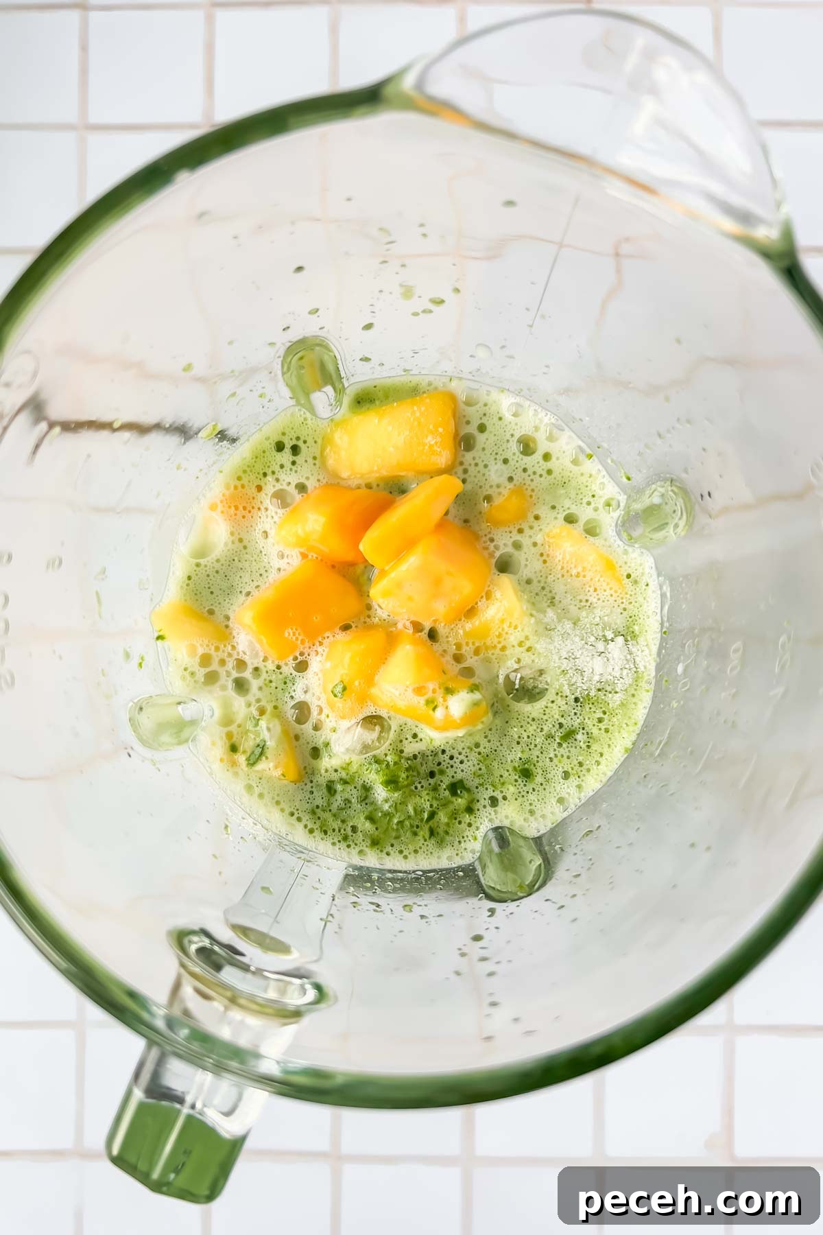 Mango Spinach Smoothie Recipe for Energy and Glow 5 frozen mangoes, milk, vanilla protein powder, and spinach water all added to glass blender.