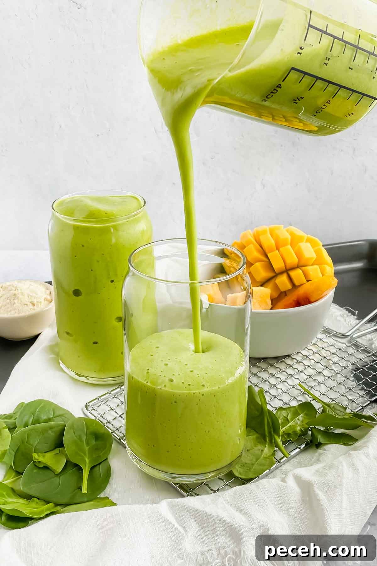 Mango Spinach Smoothie Recipe for Energy and Glow 7 mango spinach smoothie being poured into glass cup.